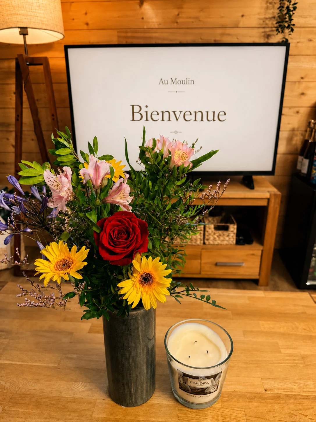 Bouquet de fleurs et bougie devant l’écran de bienvenue personnalisé d’Au Moulin