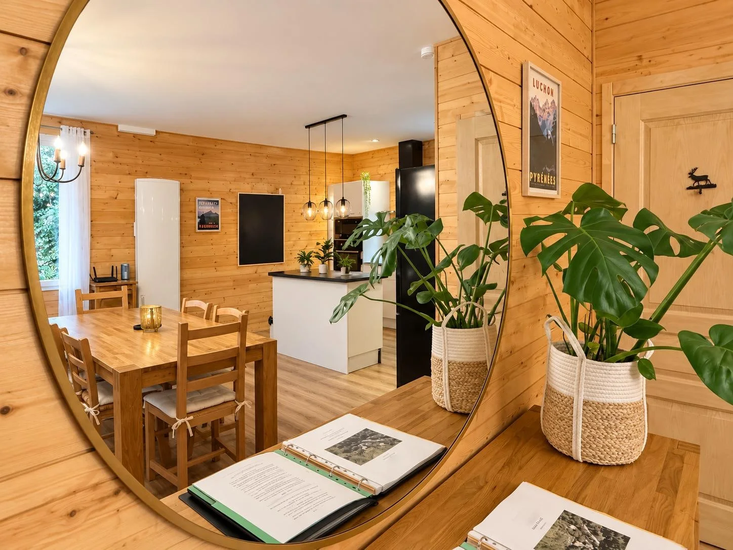 Un grand miroir, une plante et le livret d’accueil ouvert sur le buffet