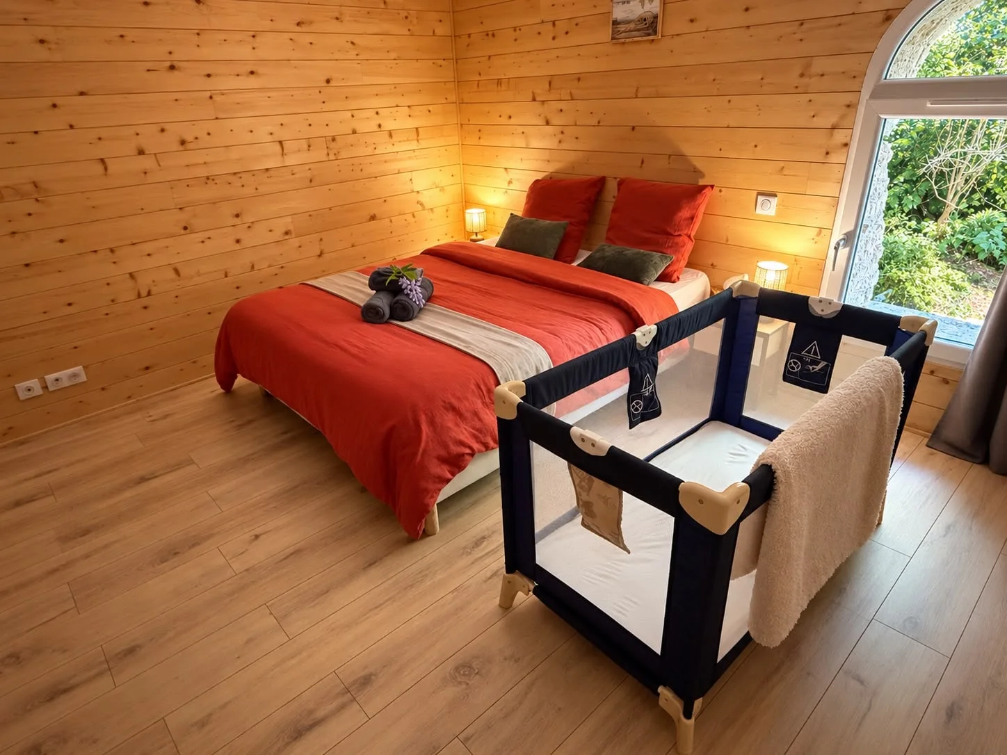 Chambre rouge en boiseries, lit double près de la fenêtre et lit bébé au premier plan