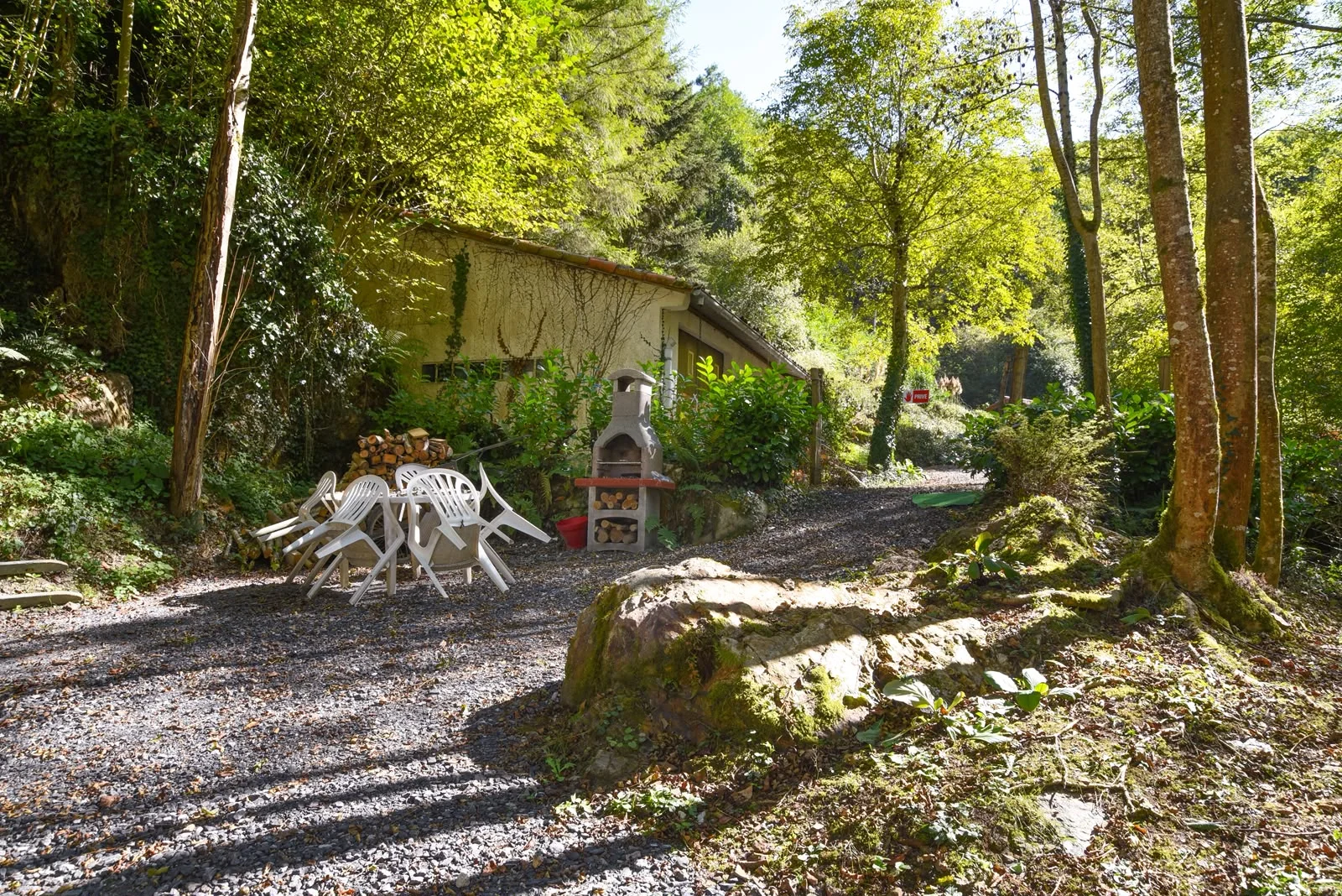 Wooded outdoor area with table and fixed stone barbecue