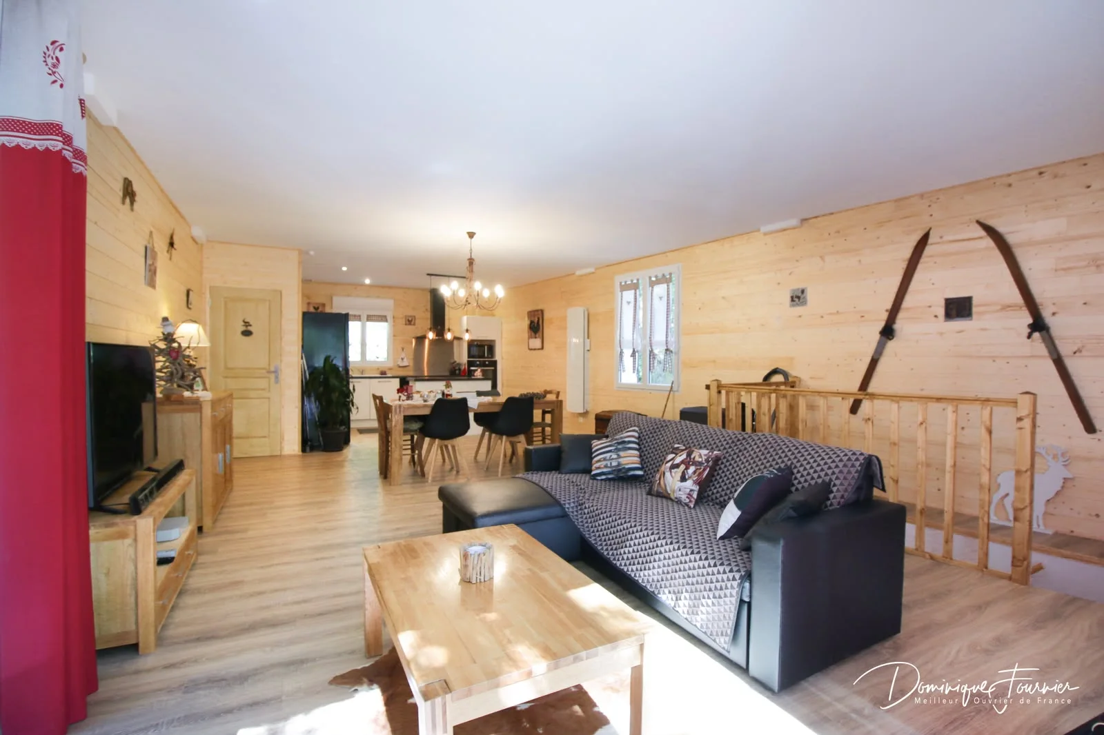 Grande pièce de vie en bois avec salon, table et cuisine équipée