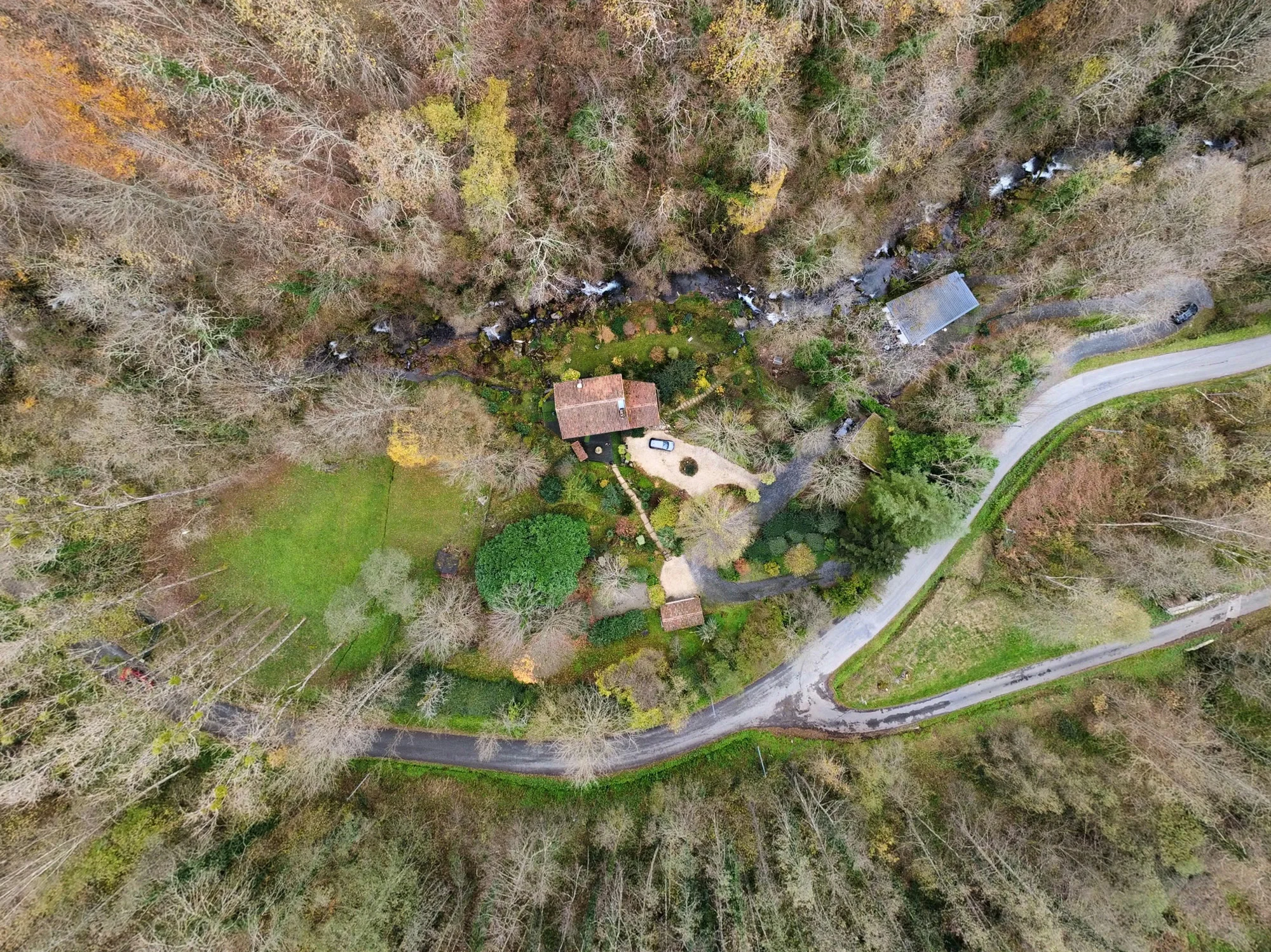 Vue aérienne du Moulin et de sa rivière au milieu des arbres en automne