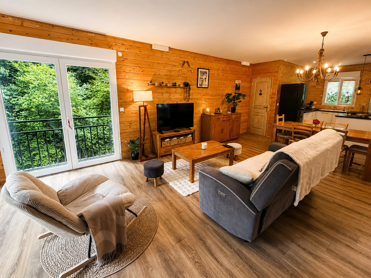 Grande pièce de vie en bois avec salon, table et cuisine équipée